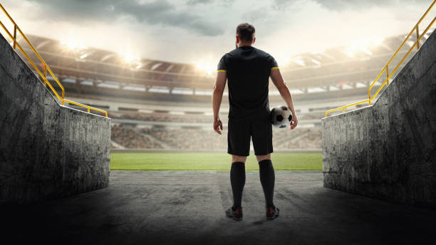istock Soccer player standing with ball in entrance, looking at empty 3D stadium. Motivation for athletes showing determination and anticipation before big game. 1997514773