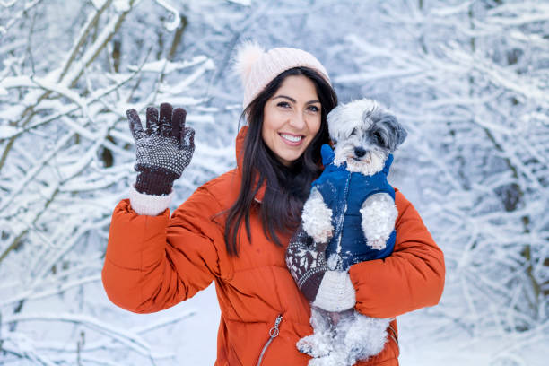Woman hugging her havanese dog in the winter forest