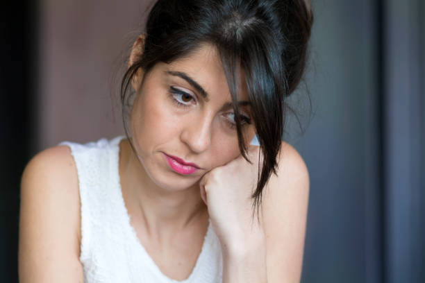 Pensive young woman outdoors in Paris looks down.