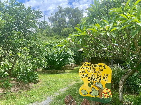 Horizontal landscape of public space community gardens with sign saying ‘Gardening and sharing in the wisdom of elders' Space , at Mullumbimby Community Gardens NSW Australia