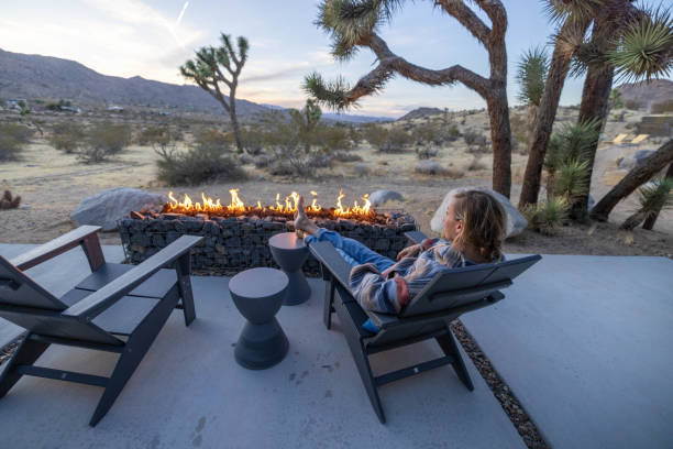 istock Under the Dusk Sky: A Young Woman Finds Warmth by the Outdoor Fire Pit. 1997625818
