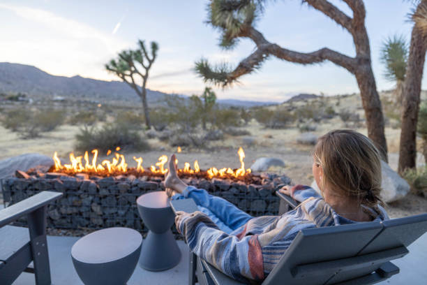 istock Under the Dusk Sky: A Young Woman Finds Warmth by the Outdoor Fire Pit. 1997626492