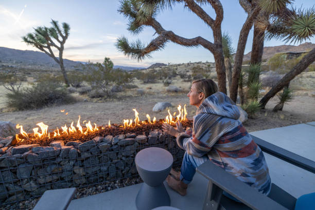 istock Under the Dusk Sky: A Young Woman Finds Warmth by the Outdoor Fire Pit. 1997626493
