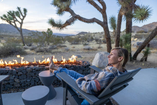 istock Under the Dusk Sky: A Young Woman Finds Warmth by the Outdoor Fire Pit. 1997627010