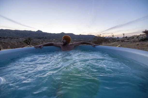 istock Man relaxing in hot bath tub outdoors at dusk 1997628615