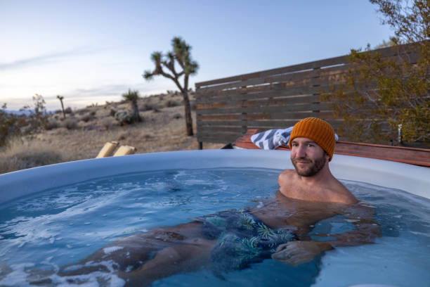 istock Man relaxing in hot bath tub outdoors at dusk 1997628618