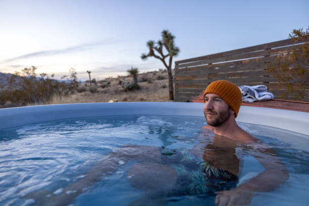 istock Man relaxing in hot bath tub outdoors at dusk 1997628622