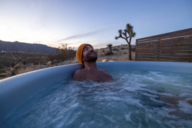 istock Man relaxing in hot bath tub outdoors at dusk 1997630216