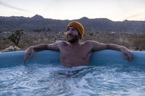 istock Man relaxing in hot bath tub outdoors at dusk 1997630229
