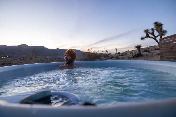 istock Man relaxing in hot bath tub outdoors at dusk 1997630738
