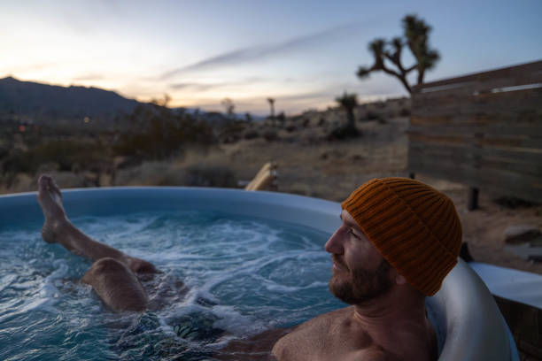 istock Man relaxing in hot bath tub outdoors at dusk 1997631801