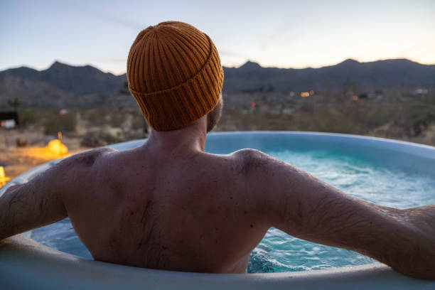 istock Man relaxing in hot bath tub outdoors at dusk 1997631806