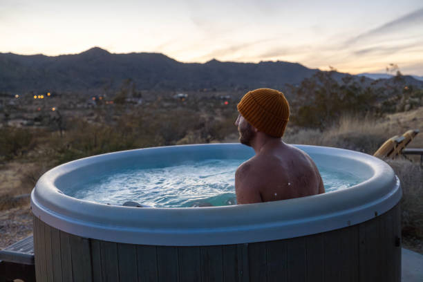 istock Man relaxing in hot bath tub outdoors at dusk 1997631815