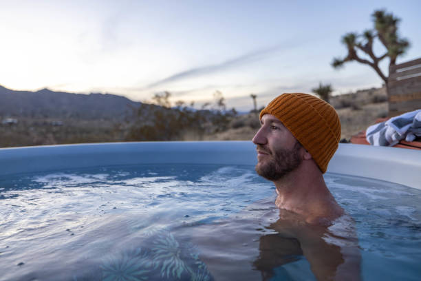 istock Man relaxing in hot bath tub outdoors at dusk 1997632325