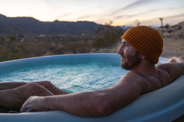 istock Man relaxing in hot bath tub outdoors at dusk 1997632330