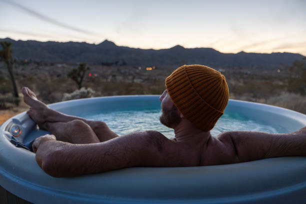 istock Man relaxing in hot bath tub outdoors at dusk 1997632344