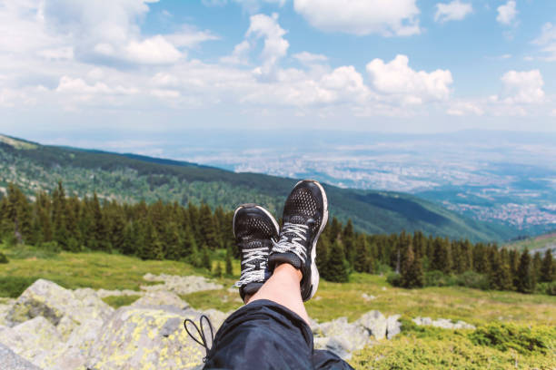Personal perspective of woman  relaxing on top of Rila Mountain . Feet view . Travel vacations concept