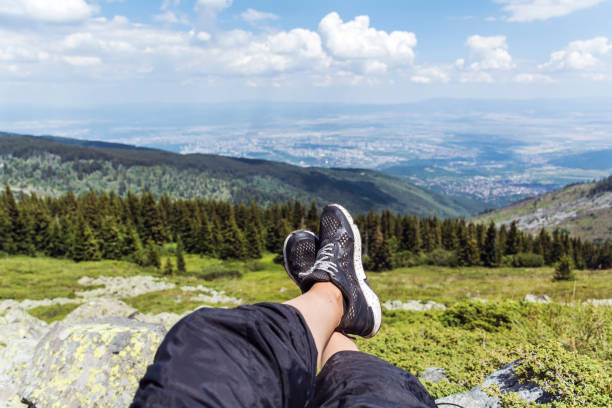 Personal perspective of woman  relaxing on top of Rila Mountain . Feet view . Travel vacations concept