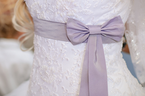 A closeup of a woman adjusting the bow on the white beautiful wedding dress