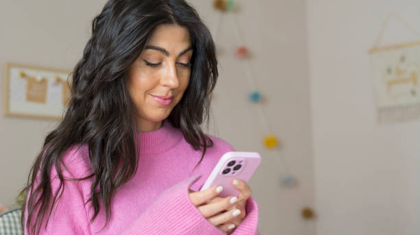 istock Smiling Woman using her phone at home 1997668464