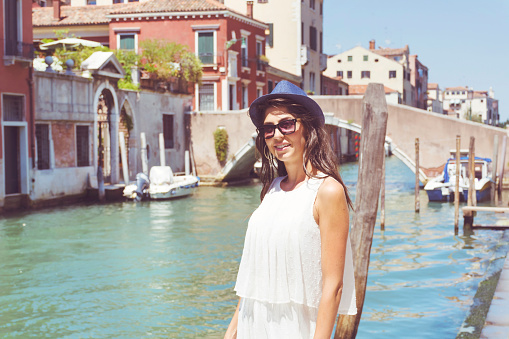 Beautiful woman enjoys the view to a canal in Venice
