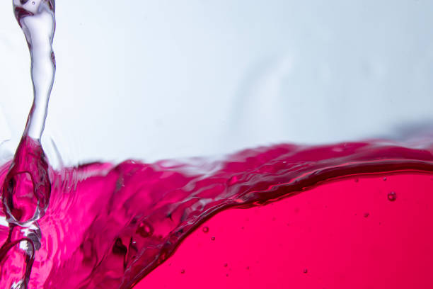 A splash of vivid red liquid caught mid-air, forming an abstract shape with droplets scattering around against a clean white background, frozen in motion with striking detail and texture.