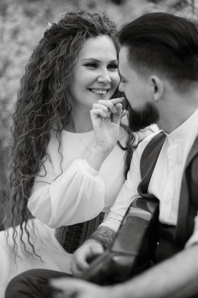 istock a bearded groom plays a stringed instrument and a girl sits in a spring meadow 1997701333
