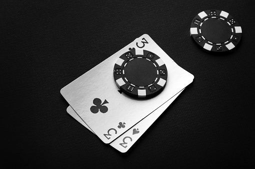 A poker game with a winning combination of one pair. Chips and playing cards on a black table.