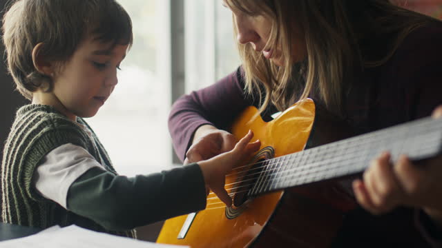 Mother and son playing guitar together at home
