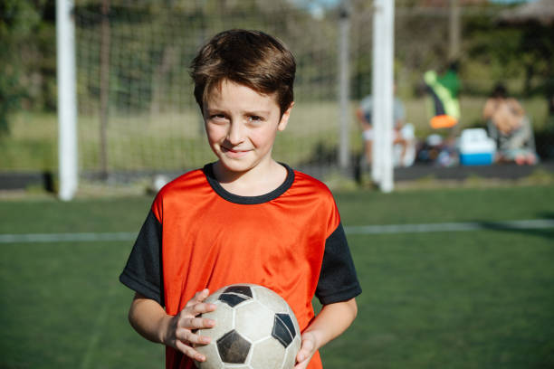 istock Confident Young Boy Holding Soccer Ball on Field 1997719512