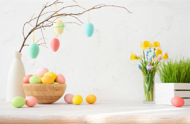 istock Painted easter eggs on twig in bowl on table with spring flowers and green grass 1997771892