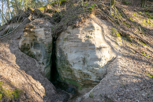 landscape with sandstone rock outcrop and cave, devil's cave near Vaidavmuiza, Valmiera county, Latvia, spring
