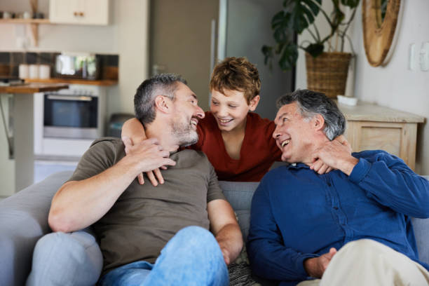 Little boy laughing with his dad and grandpa during a visit together Cute young boy laughing with his father and grandfather in their living room at home during a visit father son grandfather fathers day stock pictures, royalty-free photos & images