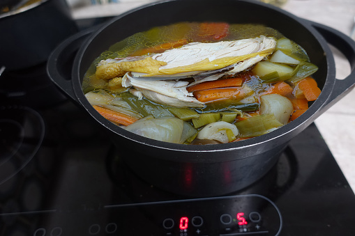 Chicken being cooked in a broth with various vegetables  Traditional French cuisine 
Poule au pot