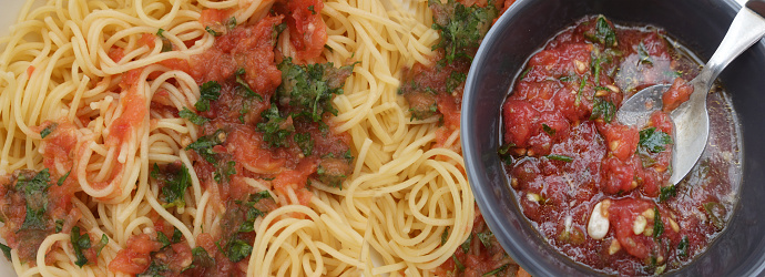 Boiled spaghetti served with raw tomato sauce and pine nuts