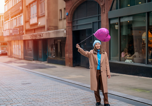 happy asian woman with a heart-shaped balloon falling a love, having a fun day, walking around  an English city Lifestyle, tourism, valentines day, world woman's day concept