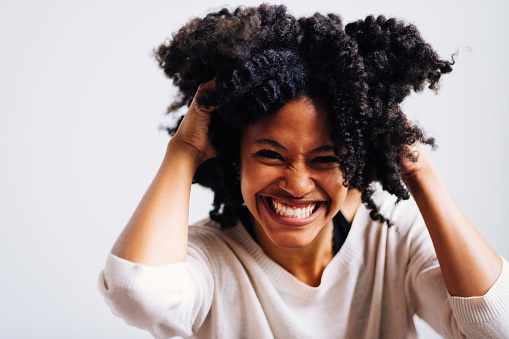 Close up of a woman with hands on afro hair laughing