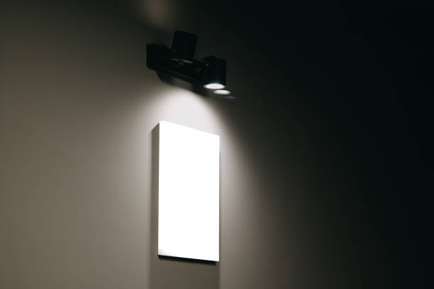 istock Blank white canvas on a grey wall lighted by a wall black modern spot lamp. 1997860756