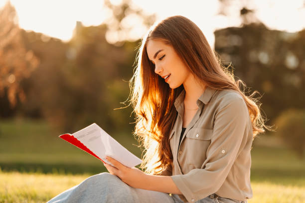 istock Cheerful young female students sitting in park and learning from a book. 1997868488
