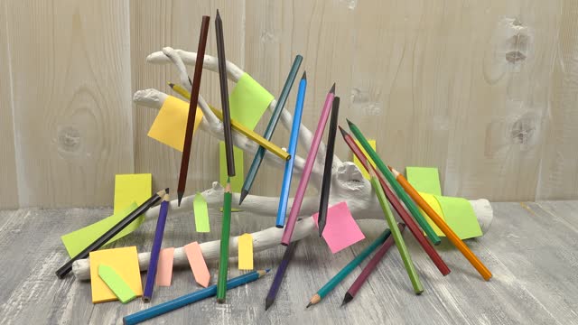 White stand made of tree branch among the colored pencils against the background of wooden boards