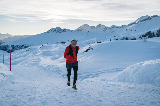 Senior trail runner bounds along snowy mountain trail , Aletsch Glacier, Valais Canton