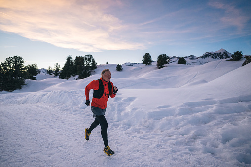 Senior trail runner bounds along snowy mountain trail , Aletsch Glacier, Valais Canton