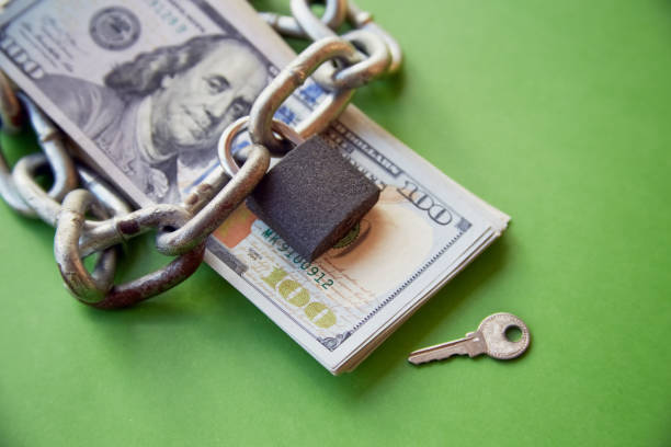 istock A chain and a closed lock lay on a stack of hundred dollar bills next to the key, locking up money, locking up financial resources, freezing accounts 1997954448