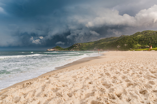 Scenic landscape on beach with sunset light before an oncoming storm. Mole beach in Florianopolis