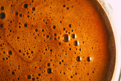 Color image depicting a macro abstract close up of bubbles in freshly brewed filter coffee.