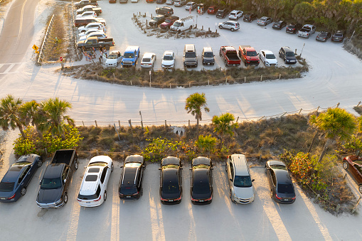 Aerial view of cars parked on ocean beach parking lot. Vacation on beachfront in Southern Florida.