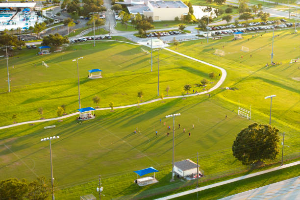 aerial view of public sports park with children engaged in football game on grass stadium at sunset. active way of life concept - football education tall sport 뉴스 사진 이미지