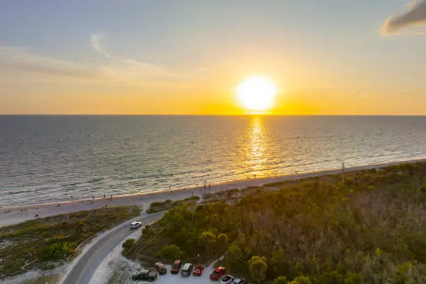 Photo of Parking lot at Blind Pass beach on Manasota Key in Englewood. Tourists cars in front of ocean beach with soft white sand in Florida. Popular vacation spot at sunset