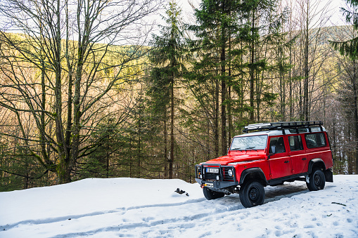 Red Land Rover parked next to the trail to Snieznik Mountains (1,423 metres ) from Kletno, winter landscape.