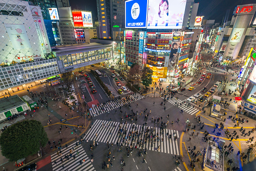 Aerial view over the iconic Shibuya Crossing and the crowds of commuters and shoppers on the streets below the colourful neon signs in the heart of Tokyo, Japan’s vibrant capital city.